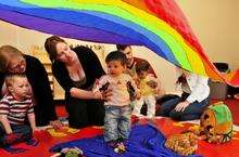 Claire Newbury holds son Ethan, 8 mths, under the rainbow during the music session.