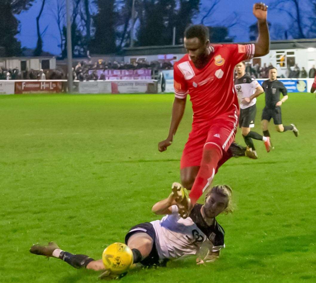 Kemo Darboe jumps over a challenge from Faversham skipper Lewis Chambers. Picture: Les Biggs