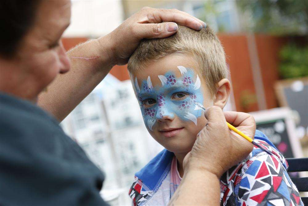 Kodi Pullen-Feaver, six, gets his face painted by Julie Feist of Crazy Face Painting