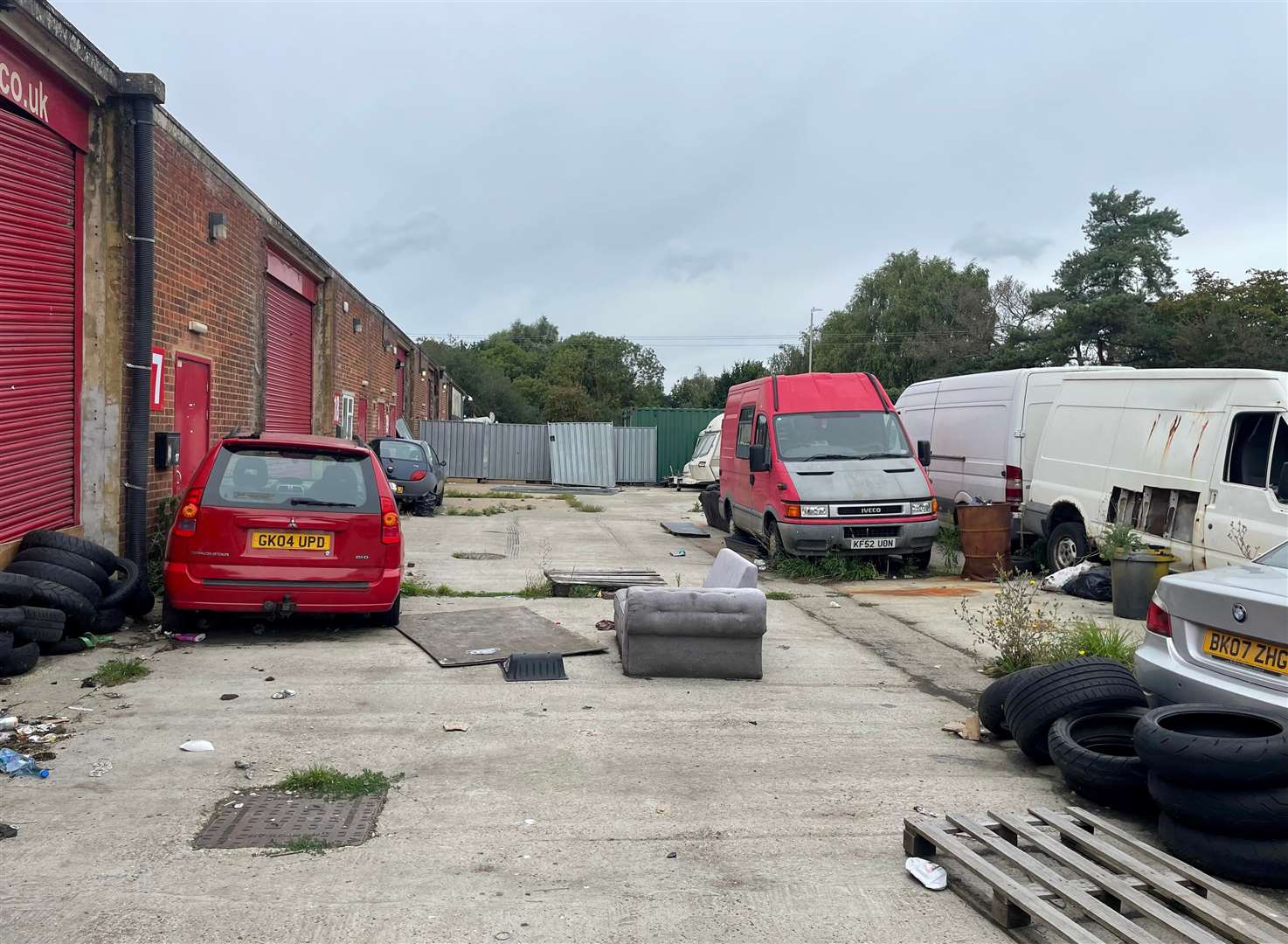Abandoned cars and rubbish are strewn around the site
