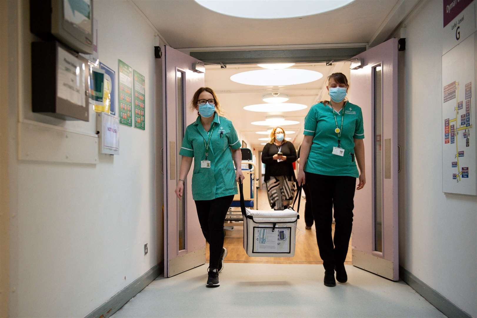 Pharmacists carry a cooler containing the Moderna vaccine at the West Wales General Hospital in Carmarthen (Jacob King/PA)