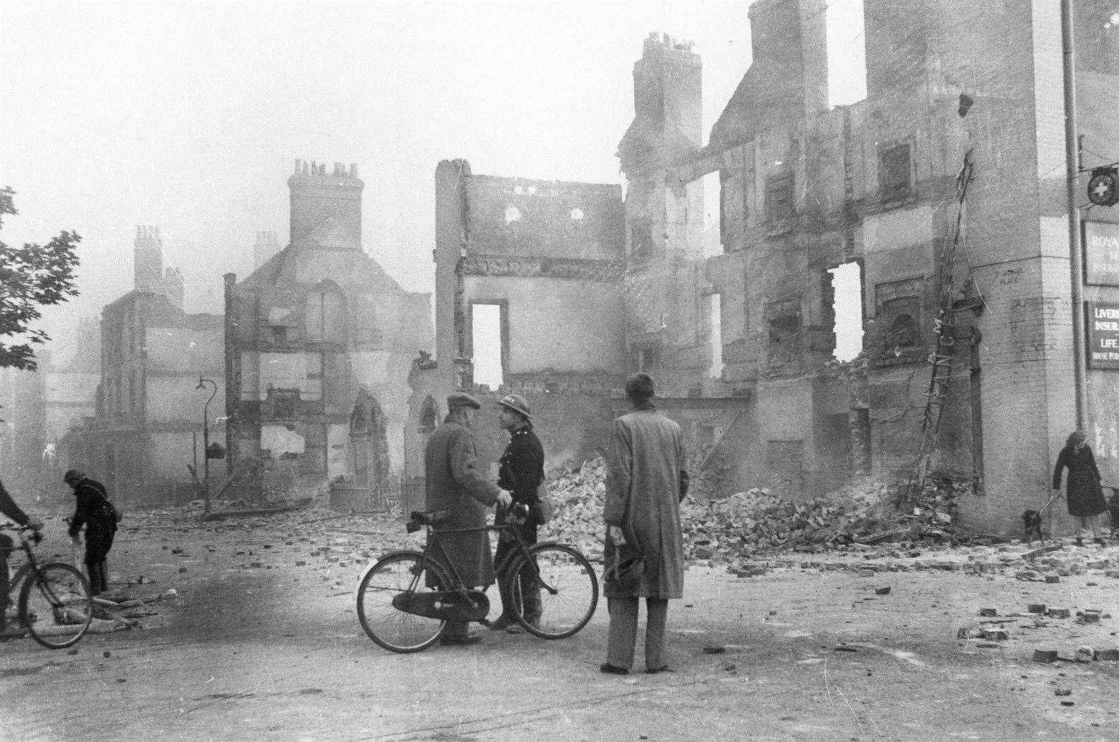 A policeman at the top end of St George's Place warns people of a suspected unexploded bomb after the June 1942 Blitz of Canterbury. Behind are the ruins of Regency buildings that were left to burn unattended