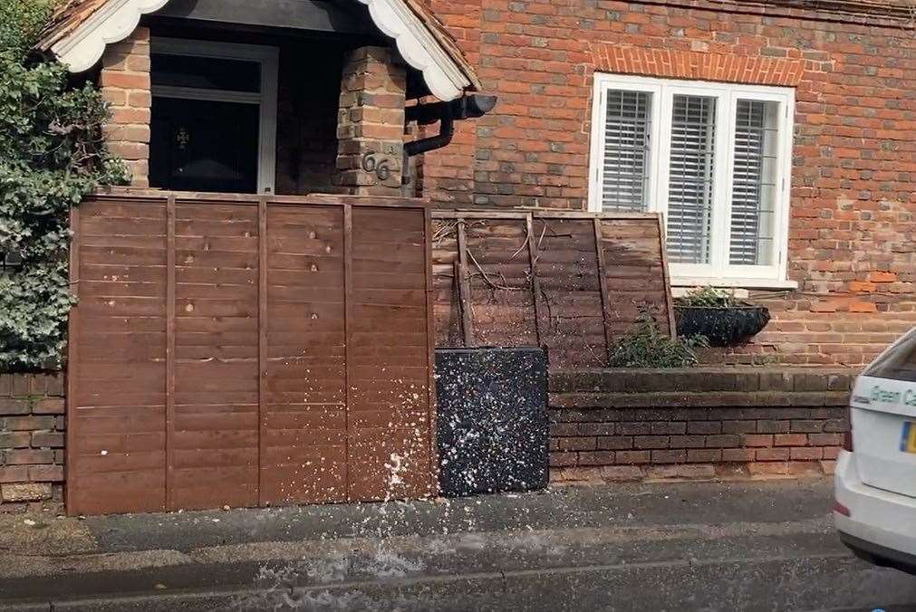 A wooden fence panel protects this home from splashes caused by the water leak in North Street, Milton Regis