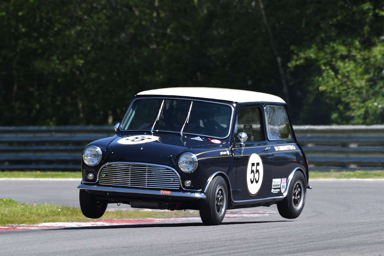 Former BTCC racer Jeff Smith flies over the kerb at Westfield bend, on his way to third place in the first Pre-66 Mini race. Picture: Simon Hildrew