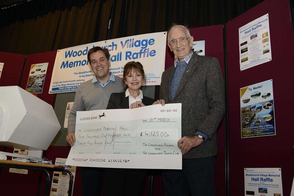 Raffle organiser Nick Jones and actress Jan Francis hand over the proceeds to Tom Thorp of Woodchurch Memorial Hall committee