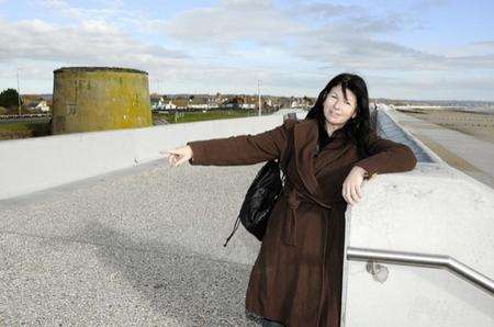 Dymchurch Sea Wall,Mandy Rossi points to where her Parents bench and plaque used to be.