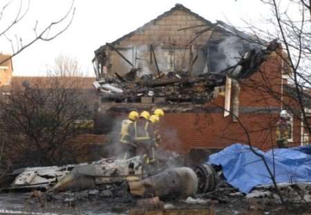 Firefighters survey the wreckage of the plane by the destroyed house. Picture: Grant Falvey