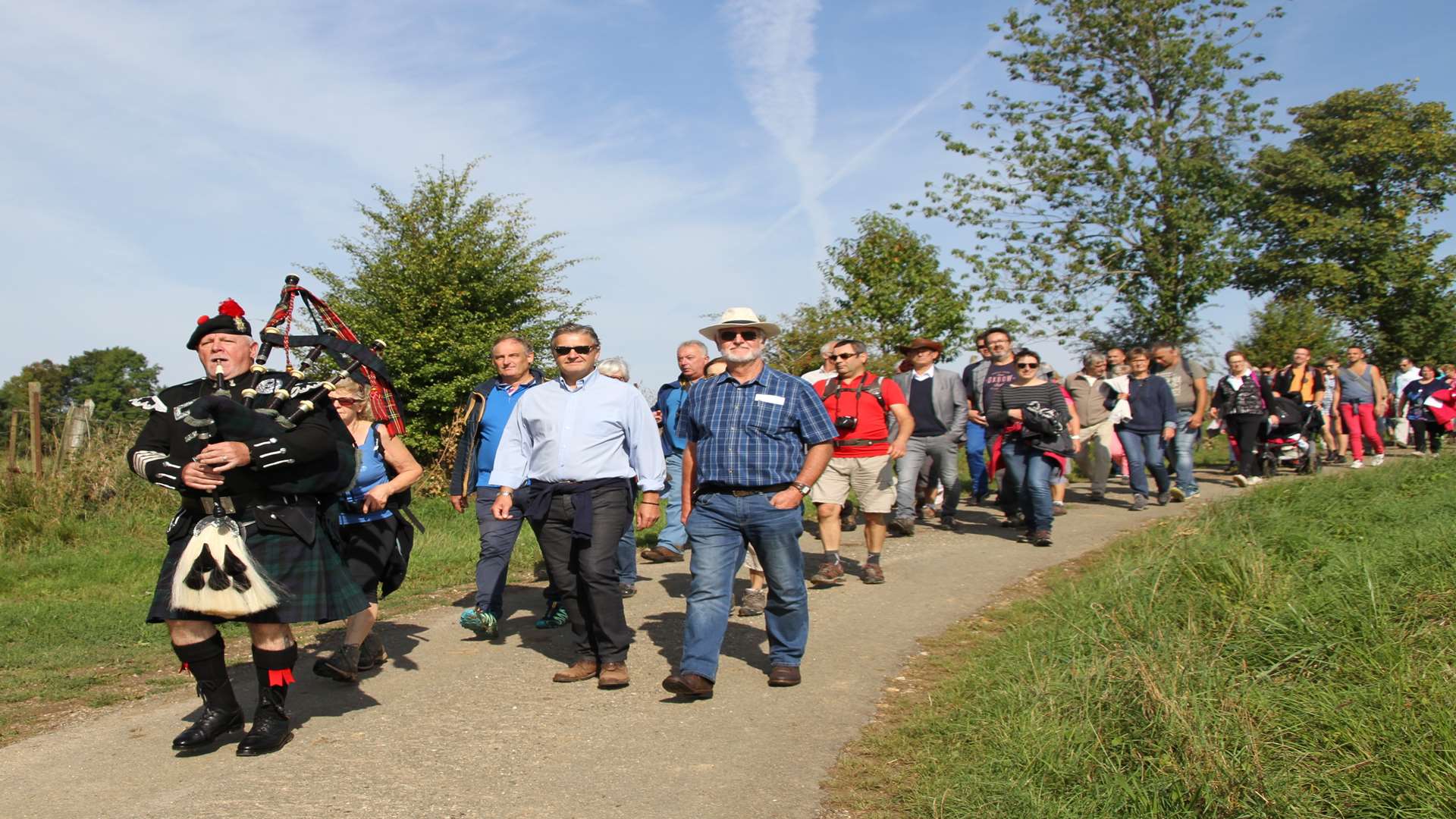 A lone Scots piper leads a group of French and English paying tribute to Sheppey First World War flying ace Major James McCudden, led by his great nephew Richard Benns (with hat) next to Keith Dobson (in light blue shirt and black trousers). Picture: Grace Dobson.