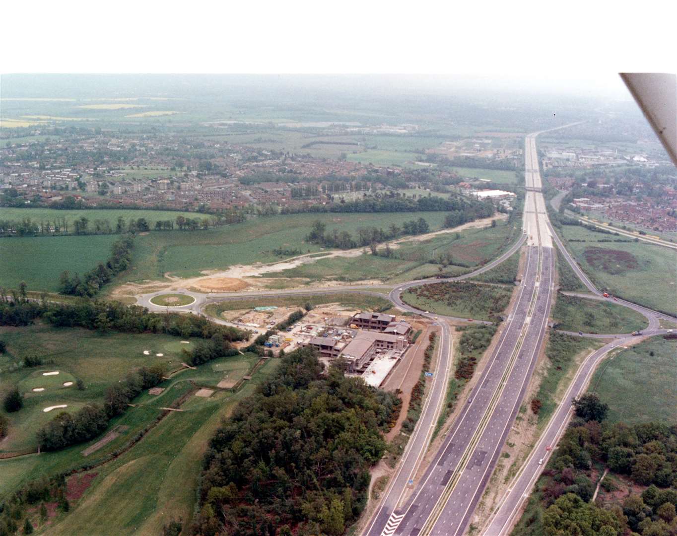 Looking coastbound down the M20 at Junction 9 for Ashford in 1991. The golf course is to the bottom left, while Eureka Leisure Park - boasting a Cineworld, hotels, and a range of restaurants - is yet to be built. The suburbs of Bybrook and Kennington can be seen to the left. Pic: Steve Salter