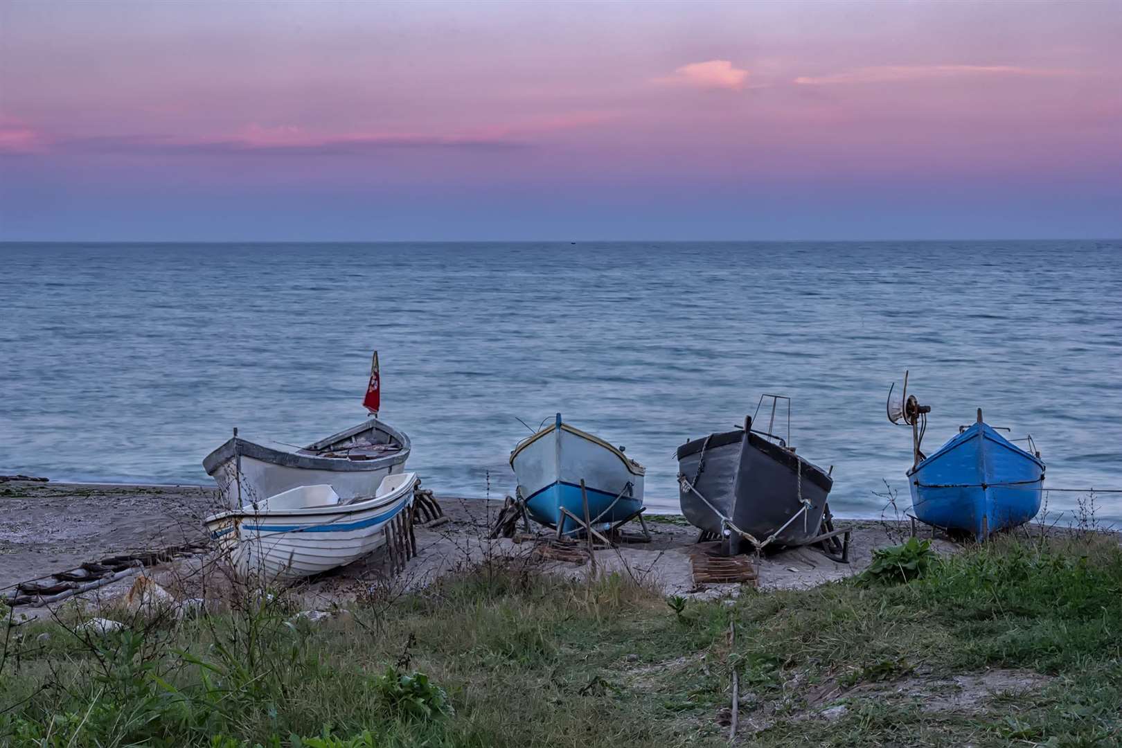 Several wooden boats on the sand after sunset on Dungeness coast