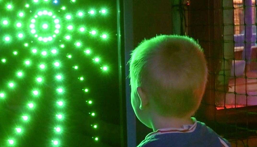 A toddler enjoying a light display at Adventure Kidz