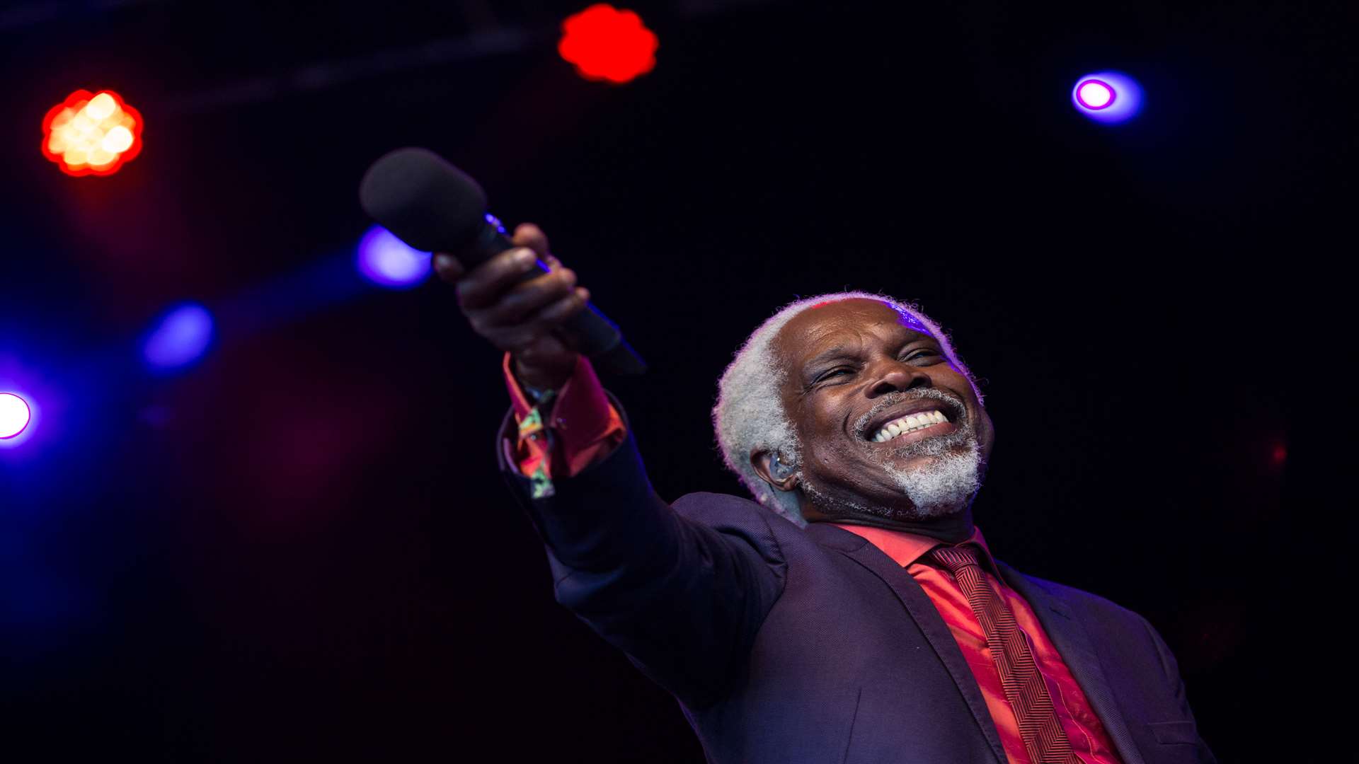 Billy Ocean holds his microphone out to the crowd