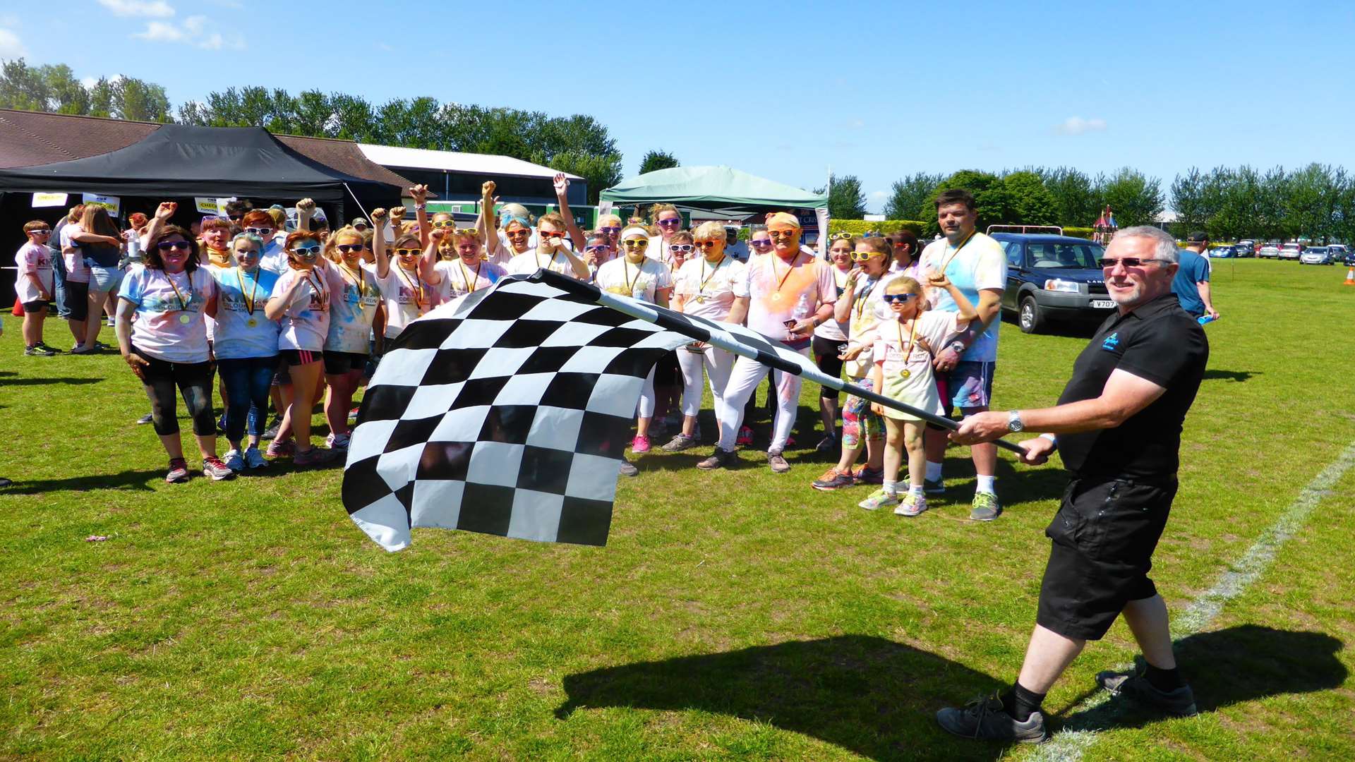 Keith Privett of BayPoint sports and leisure club, Sandwich waves the chequered flag for the KM Colour Run.