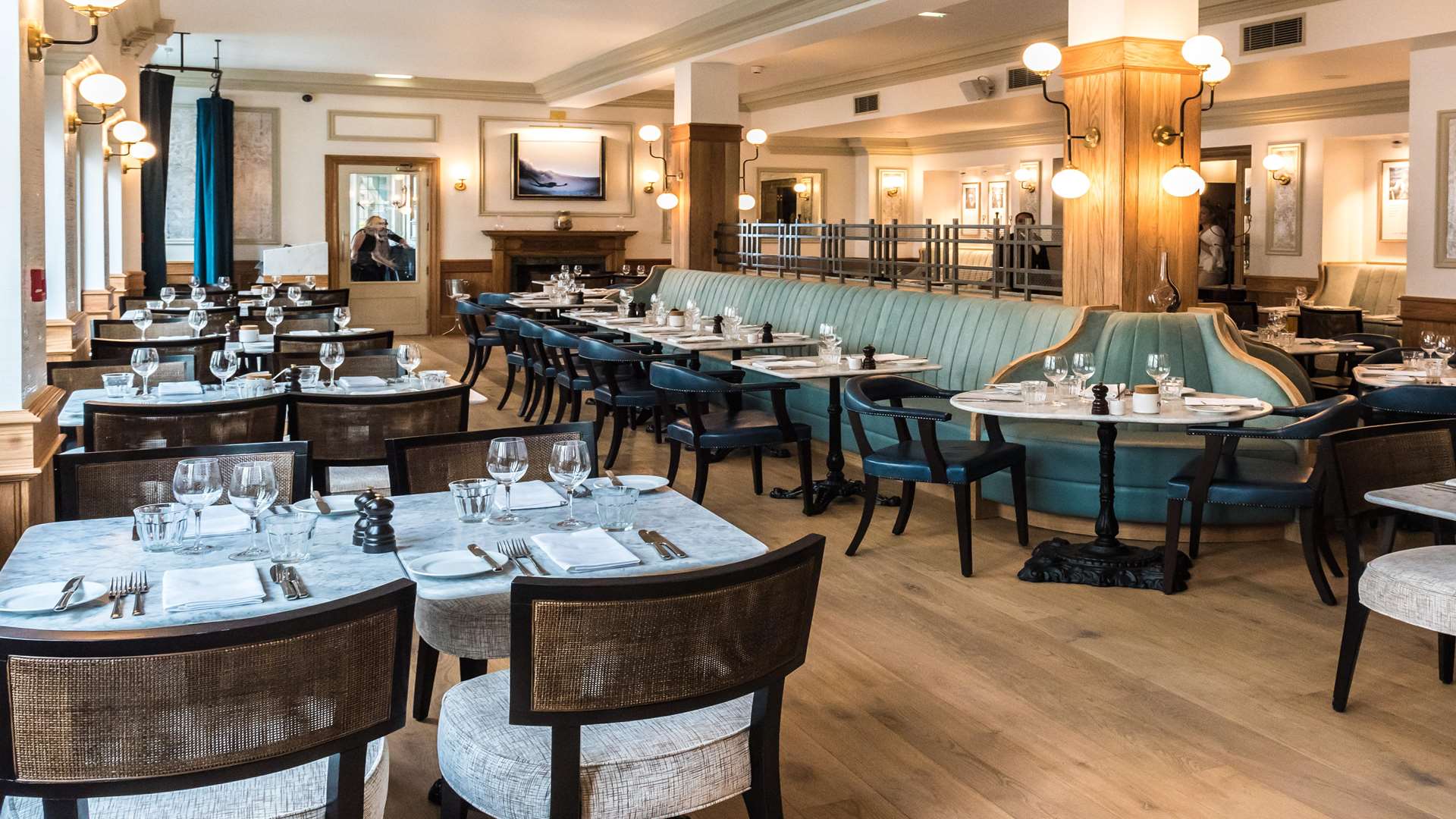 The plush teal-clad sofa is lined by marble tables that form an oval in the centre of the bistro