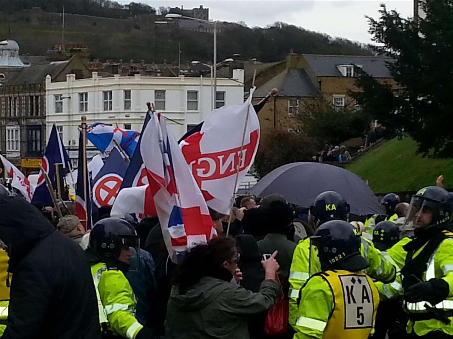 Far right marchers holding their flags and police on the day of the rioting.