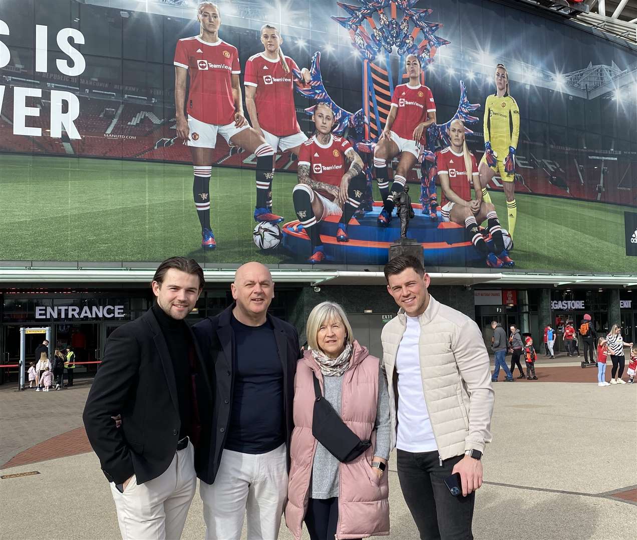 Alessia Russo's family in front of a giant photo of Alessia and her Manchester United team-mates at Old Trafford. Brothers Luca and Giorgio flank dad Mario and mum Carol