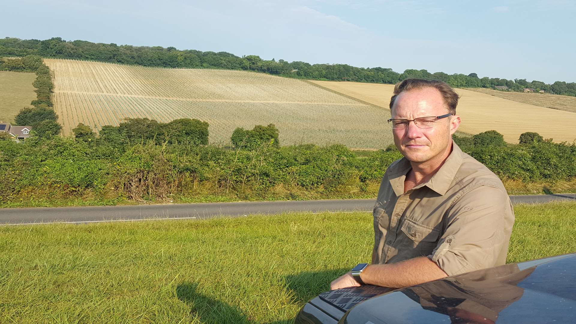 Wine maker Charles Simpson against the backdrop of a newly-planted vineyard in the Elham Valley