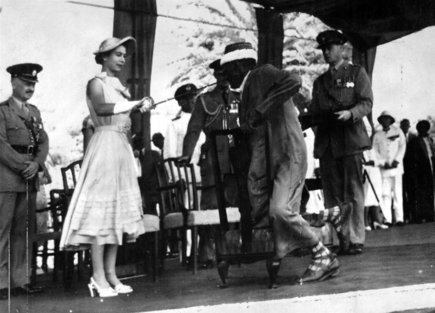 The Queen bestowing a knighthood on Seiyid Bubakr Bin Sheikh Al Kaf, Councillor of the Kathiri State in Eastern Aden, at an open-air investiture in 1954 (PA)