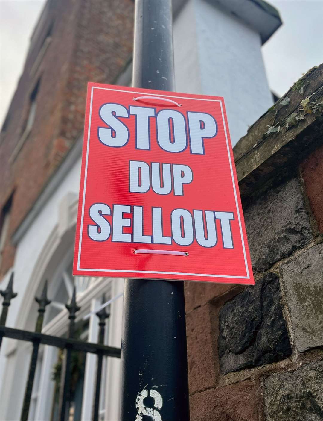 A poster says Stop DUP Sellout on a lamppost near Hillsborough Castle (Claudia Savage/PA)