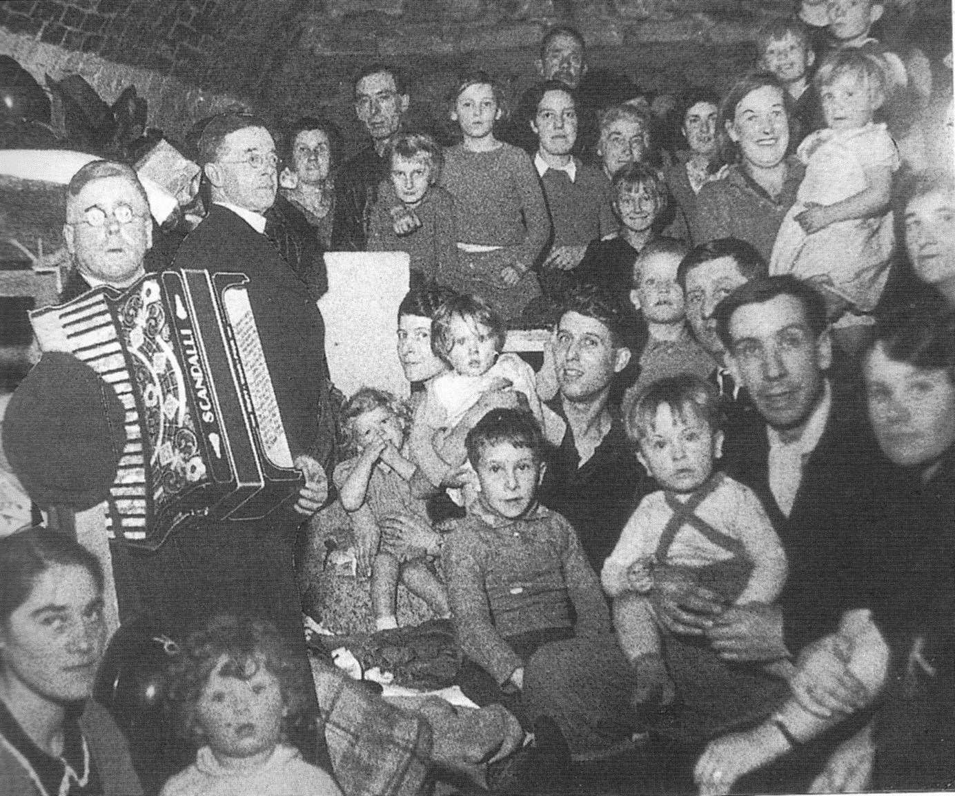 An accordion player keeps up spirits in an air-raid shelter in 1940