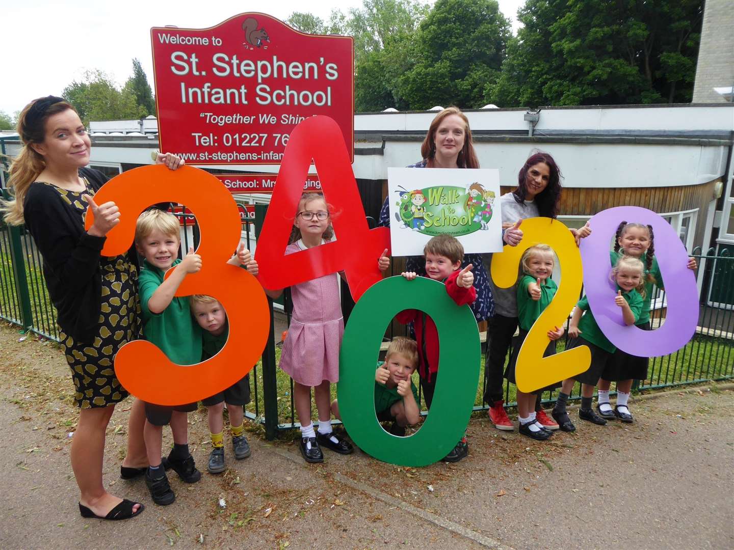 Alice Edgington, centre, and St Stephens Infant School pupils and staff announce green journey figure for district.
