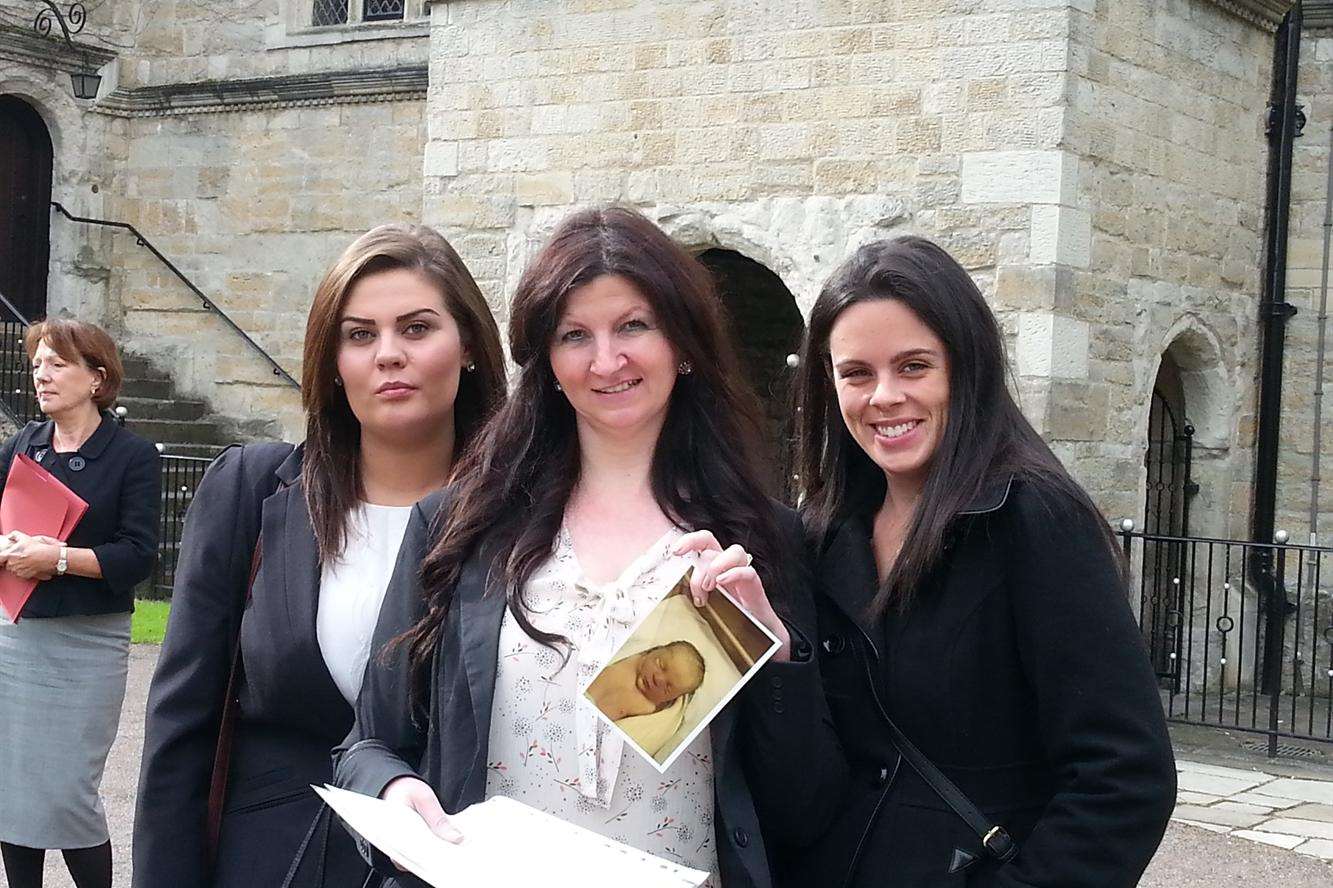 Fiona Murray (centre) holds a photo of baby Benedict after the inquest