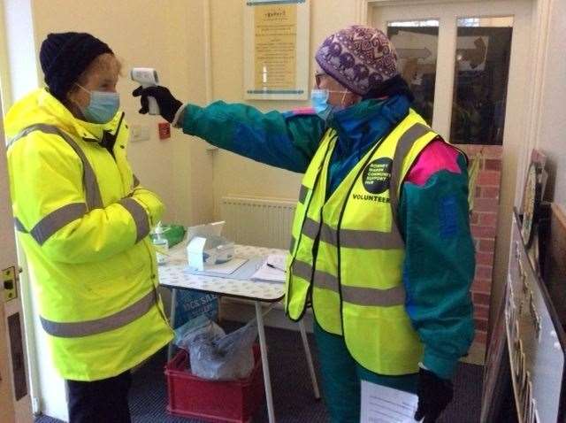 Volunteer Christine Clifton checking temperature as people arrive for vaccinations at the Old School