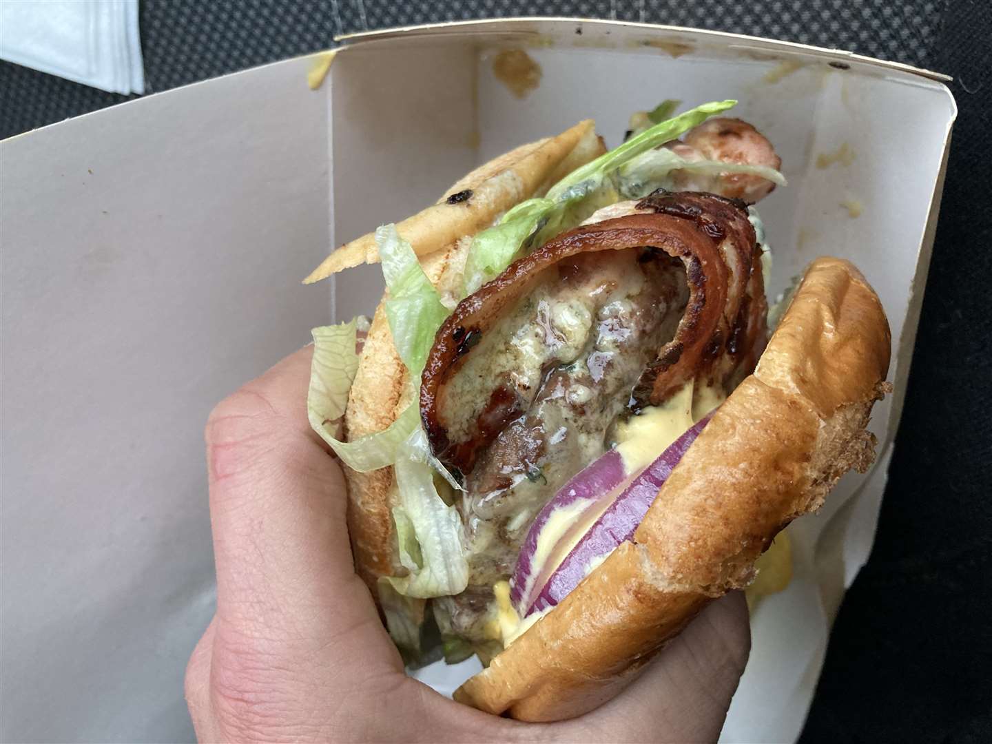 A double truffle burger featuring red onion, lettuce, beef, bacon, blue cheese and aioli
