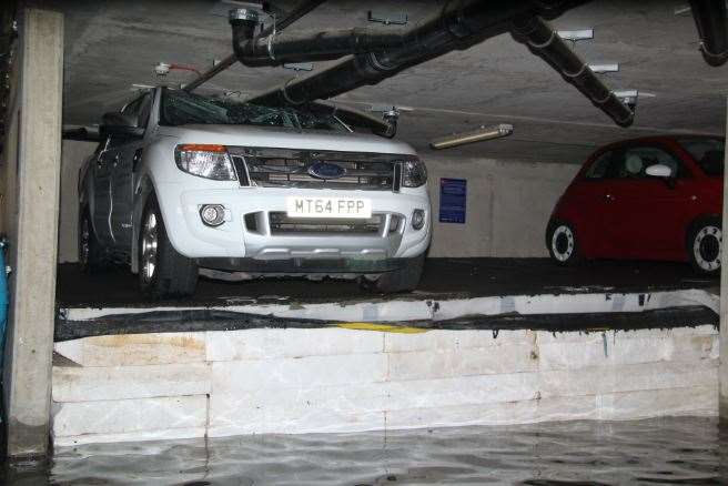 One of the cars wedged between floors of the flooded car park. Pic: @PaulWood1961