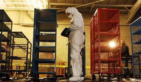 A police forensic officer inspects money cages used to store banknotes that were stolen from the depot . Picture: JOHN STILLWELL/POOL/PA
