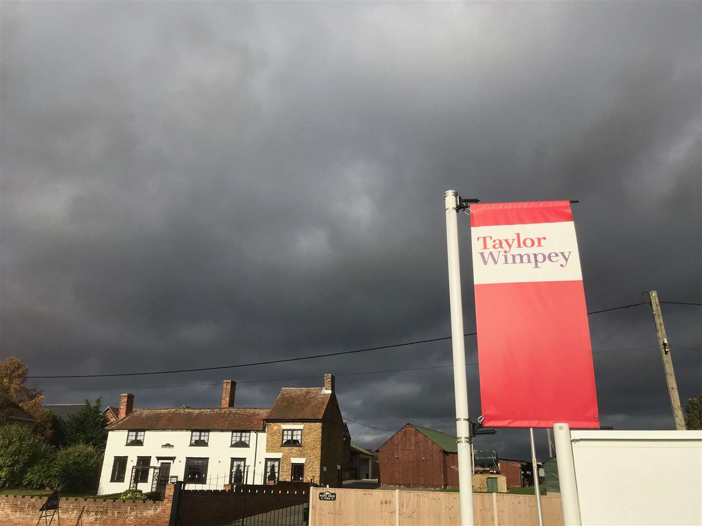 Dark clouds over a Taylor Wimpey banner in Hoo