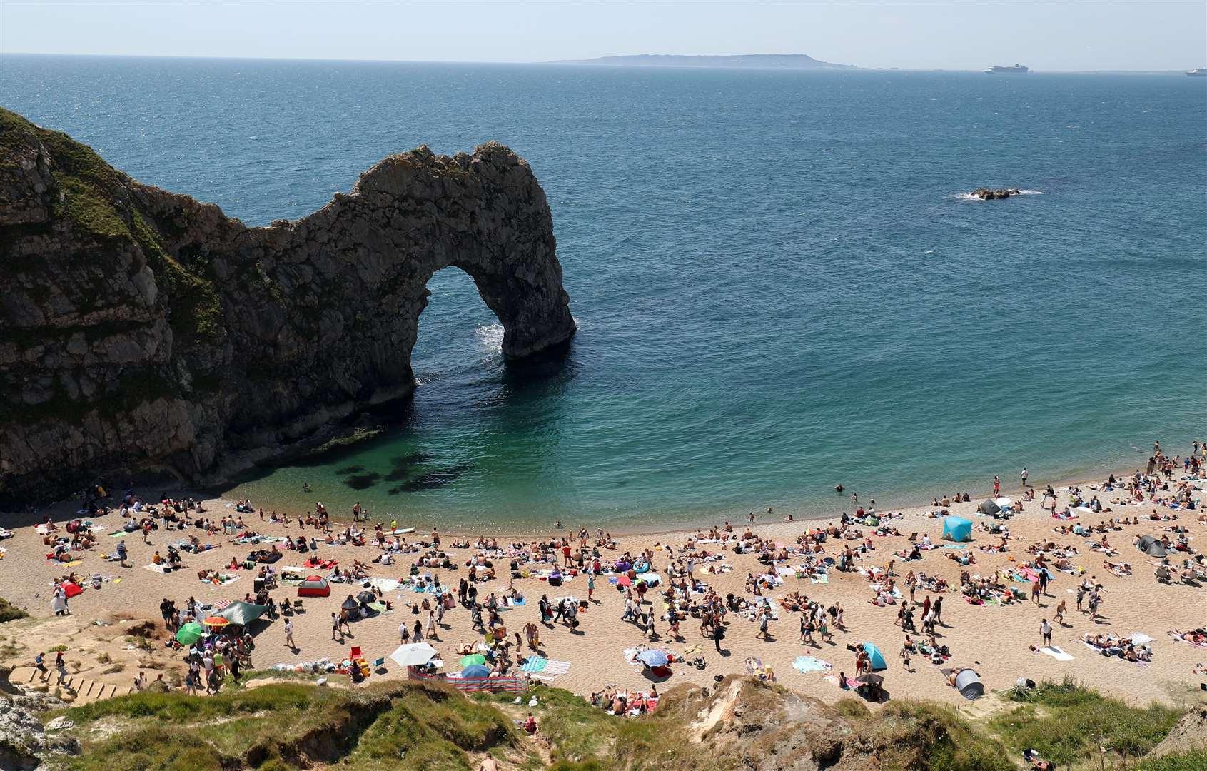 People fill the beach at Durdle Door, near Lulworth, despite Dorset Council announcing that the beach was closed to the public after three people were seriously injured jumping off cliffs into the sea (Andrew Matthews/PA)