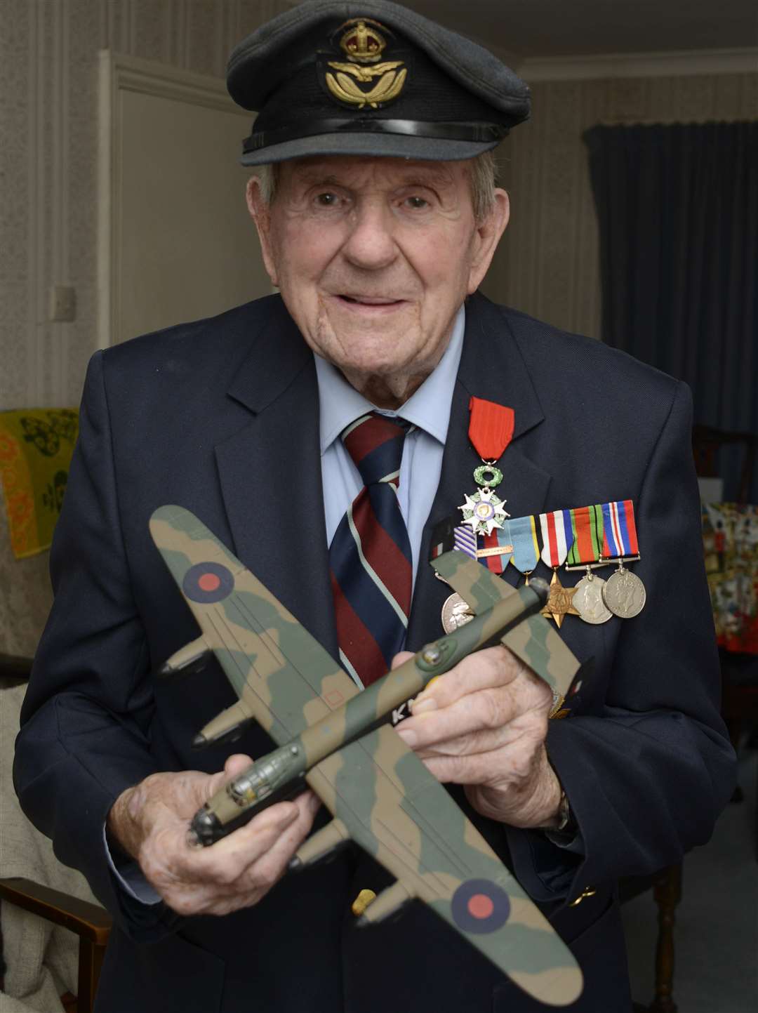 Tenterden.War Hero Colin Deverell wearing his Old Cap and holding a model of the planes he was in also his medals including Legion D'Honneur and Distinguished Flying medal.Picture: Paul Amos. (4254539)