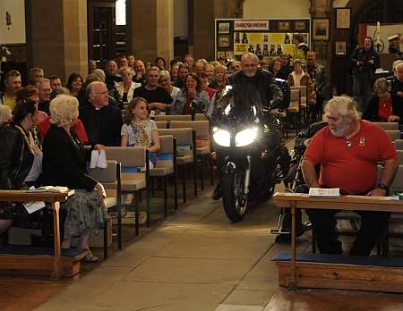 Father Colin Johnson rides his motorcycle down the aisle of Dover's Charlton Curch at the service of thanksgiving for the life and ministry of Father BIll Shergold, founder of the 69 Motorcycle Club.