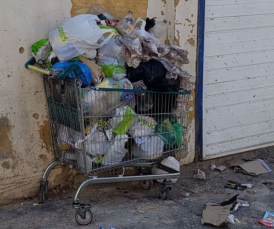 A trolley filled with rubbish bags dumped on the side of the street