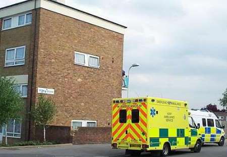 A man clings on to the balcony of an upstairs flat at Willow House, Woodberry Drive, Murston, Sittingbourne.