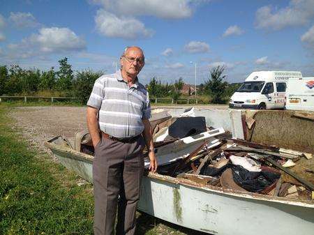 Norman Sells next to the boat filled with rubbish