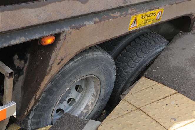 The lorry's wheels have been swallowed up by the hole