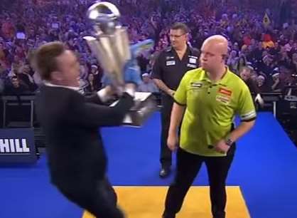 Michael van Gerwen and Gary Anderson look on as Lee Marshall grabs the world darts trophy.