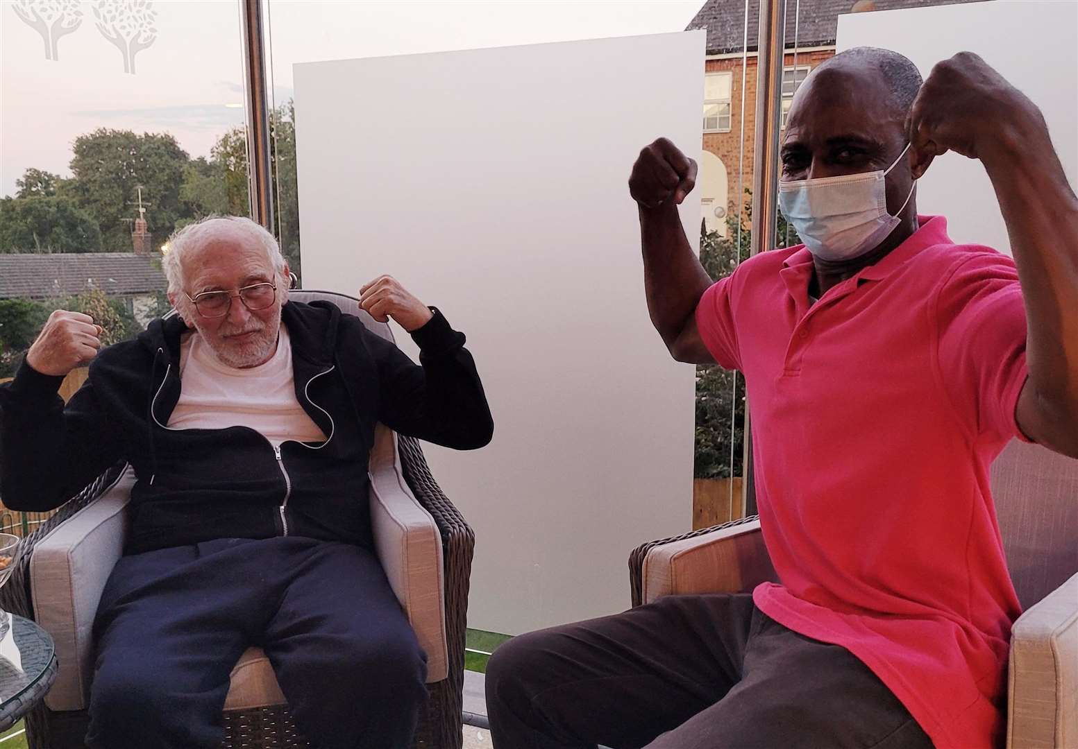 Kayode, right, flexing with a care home resident. Picture: Oakland Care