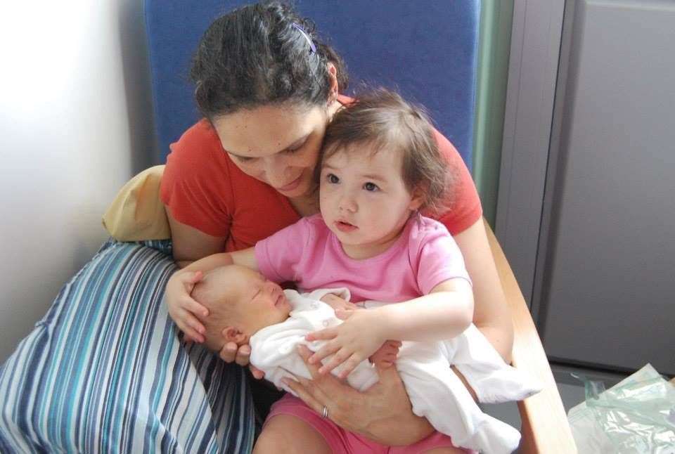 Baby Alma held by her big sister with mum Joanne