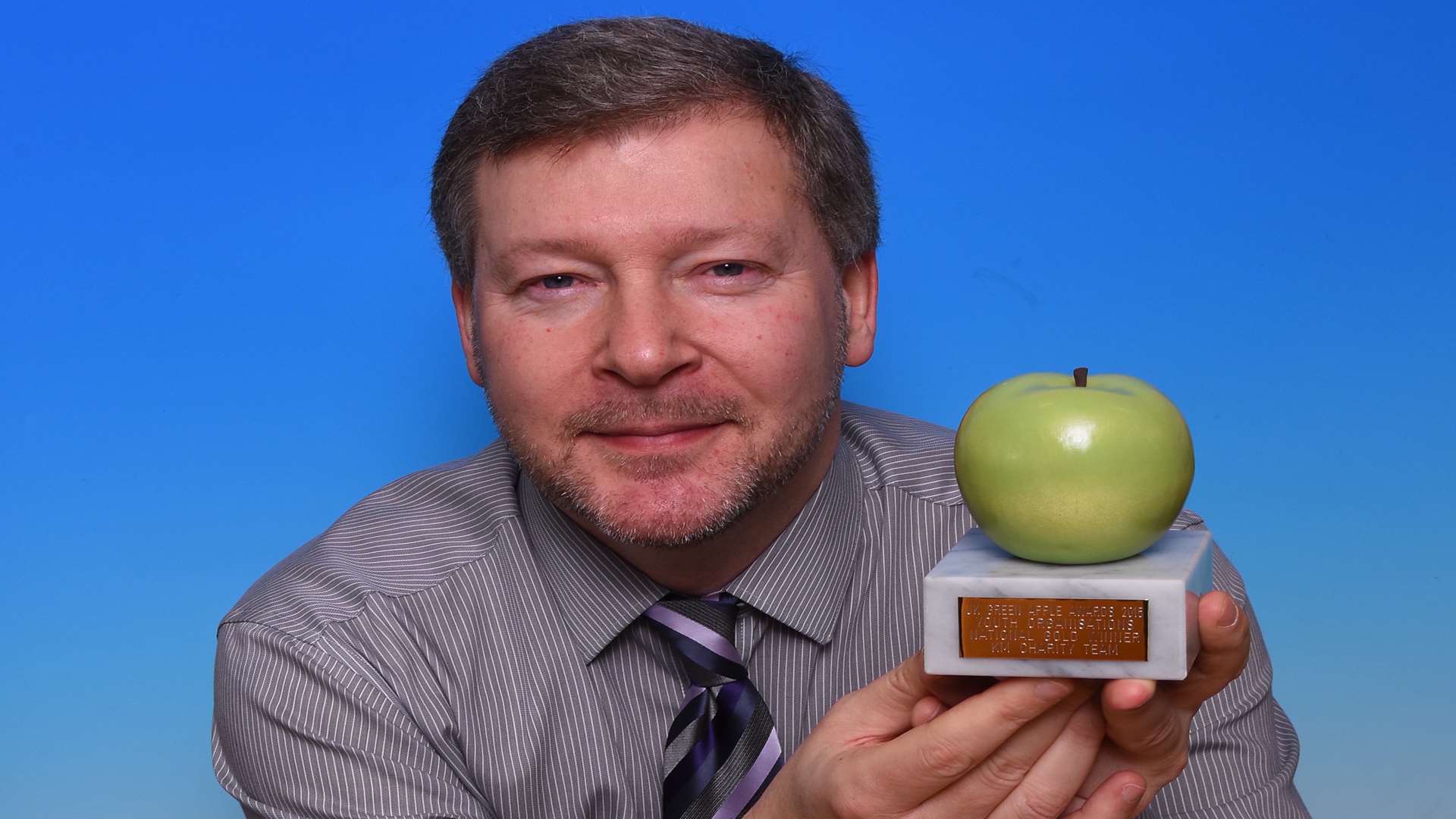 KM Charity Team chief executive Simon Dolby holds the charity's latest Green Apple Award.
