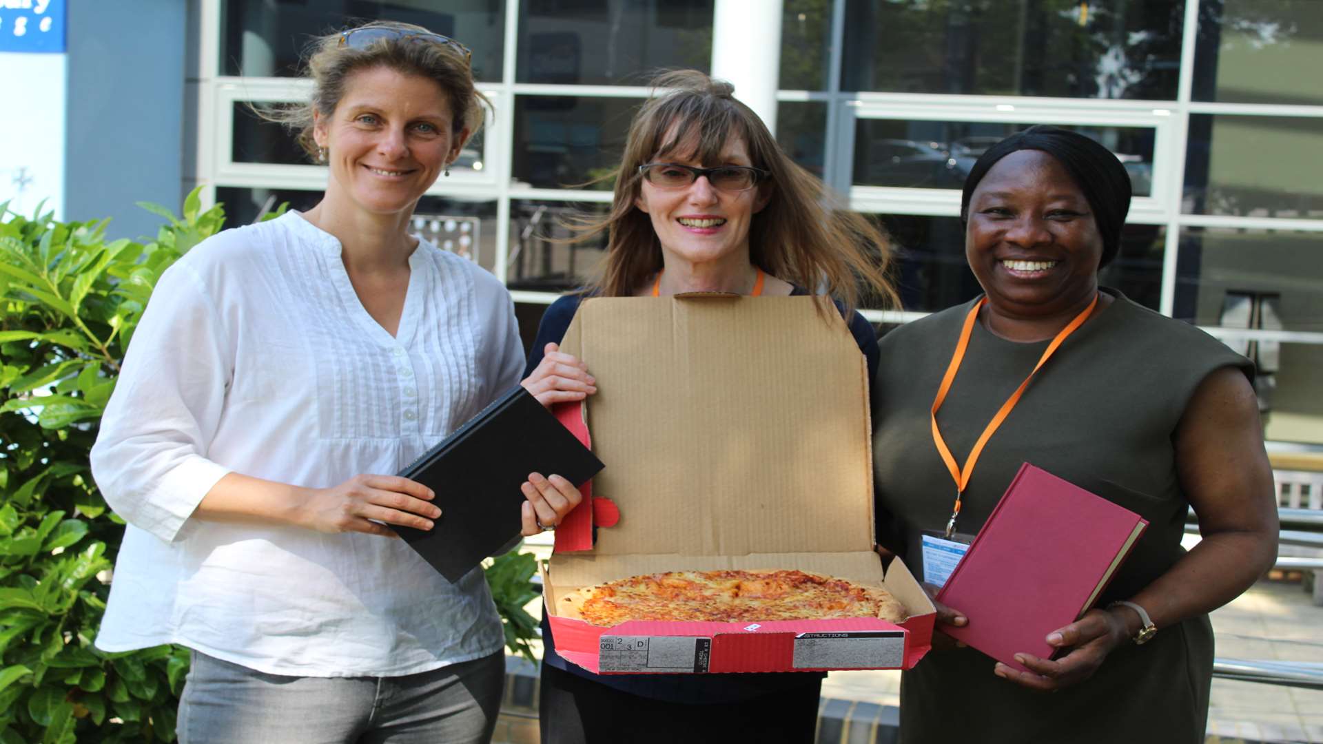 From left: Melissa Murdoch from Amity Fund with Anne Hardy and Ola Odeyemi from Kent Refugee Action Network (KRAN) receive the pizza prize to give to their winning Bookbinders group.
