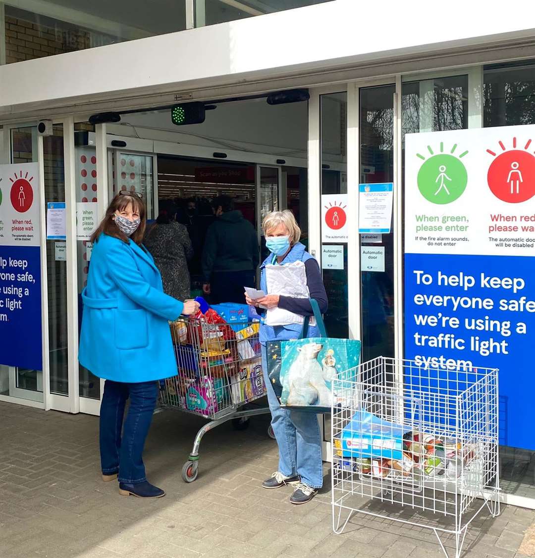 A shopper receives a donation wish list from a volunteer at Tesco