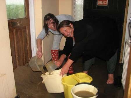 Landlady Sue Button (right) and Julie Humphries, a member her kichen staff, bale out the Fenn Bell pub with buckets.