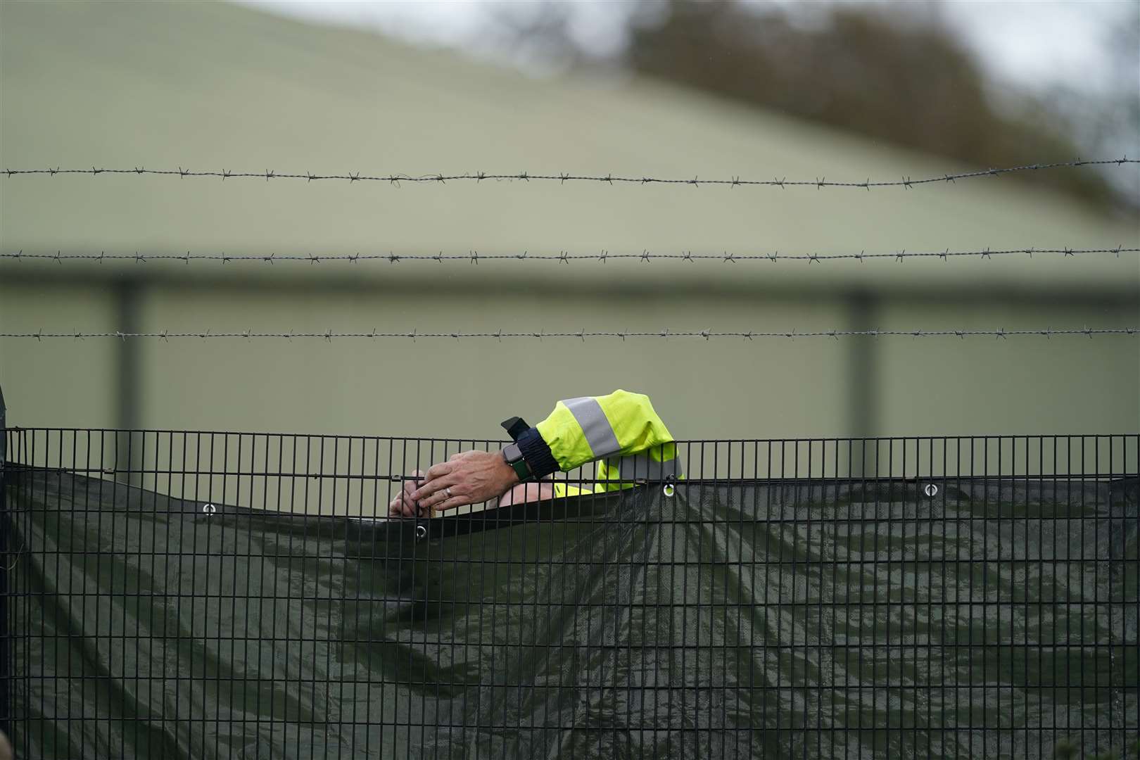 A member of security staff secures screens around the Manston immigration short-term holding facility (Gareth Fuller/PA)