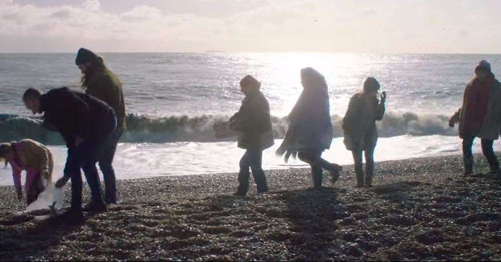 Volunteers are seen collecting litter on the beach. Photo credit: River music video by Ellie Goulding