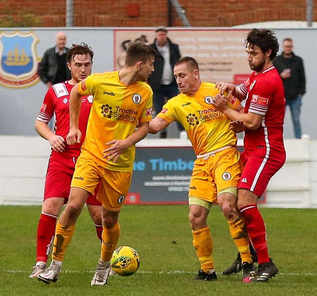 Makeshift Whitstable striker Ollie Gray is held off the ball by Burgess Hill players. Picture: Les Biggs