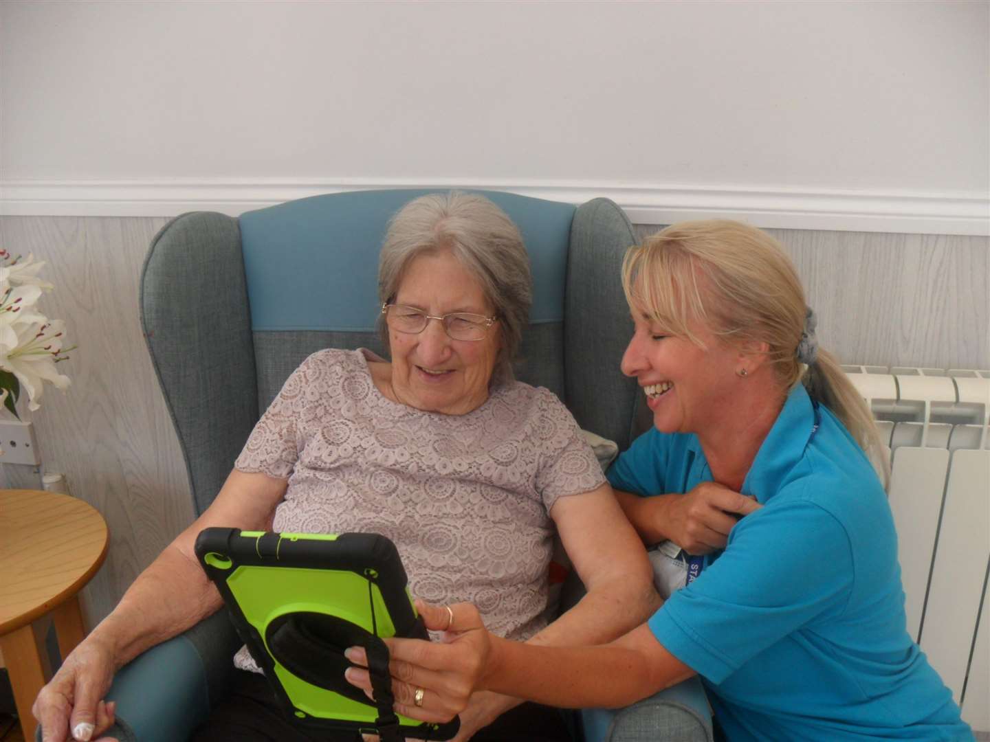 Marina Foreman, senior recreation and well-being lead at Woodstock Residential Care Centre, showing resident Barbara Woollett the tablet