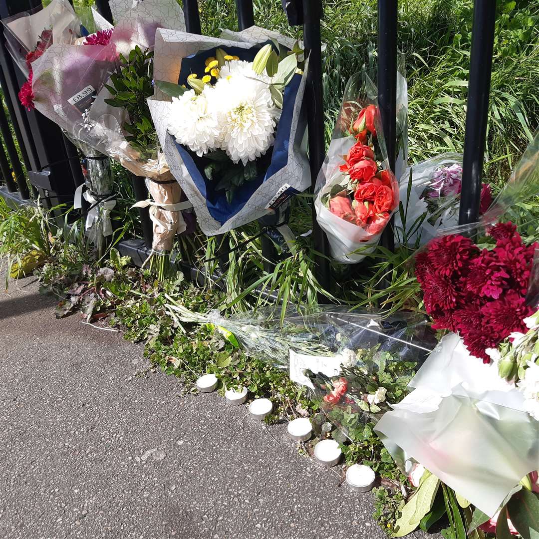 Several flowers and candles have been left by well-wishers
